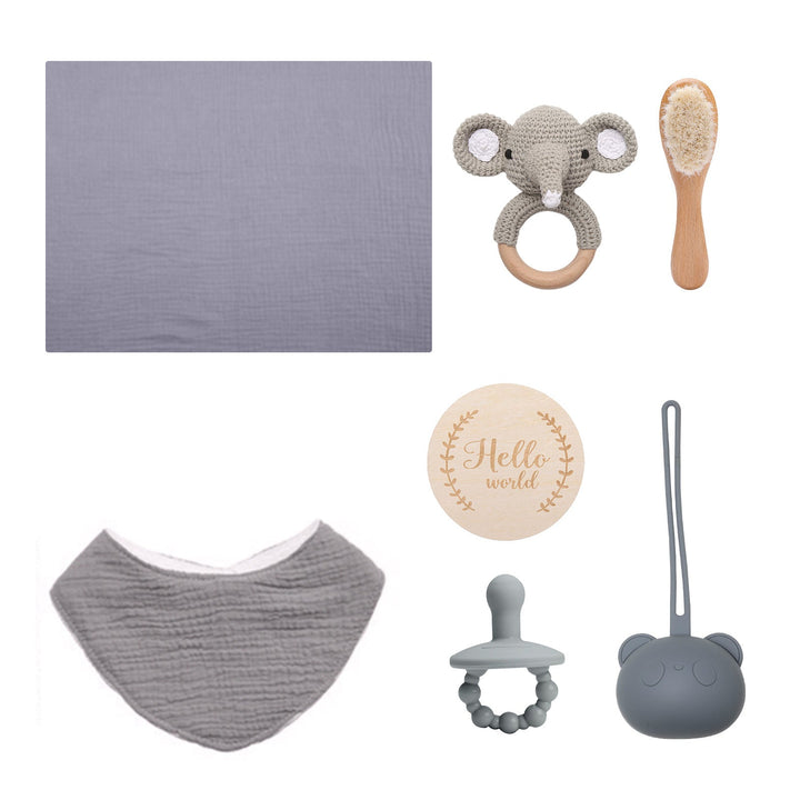 Sea Dragon Dreams baby gift set featuring a grey muslin towel, elephant rattle, wooden brush, bib, and pacifier.