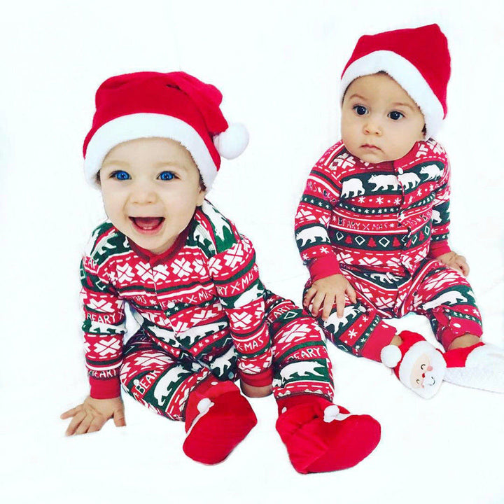 Two babies wearing Sea Dragon Dreams festive red and green Christmas rompers with Santa hats on a white background