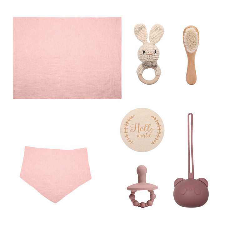 Sea Dragon Dreams baby gift set with pink muslin towel, bib, wooden brush, crochet bunny rattle, and pacifier case.