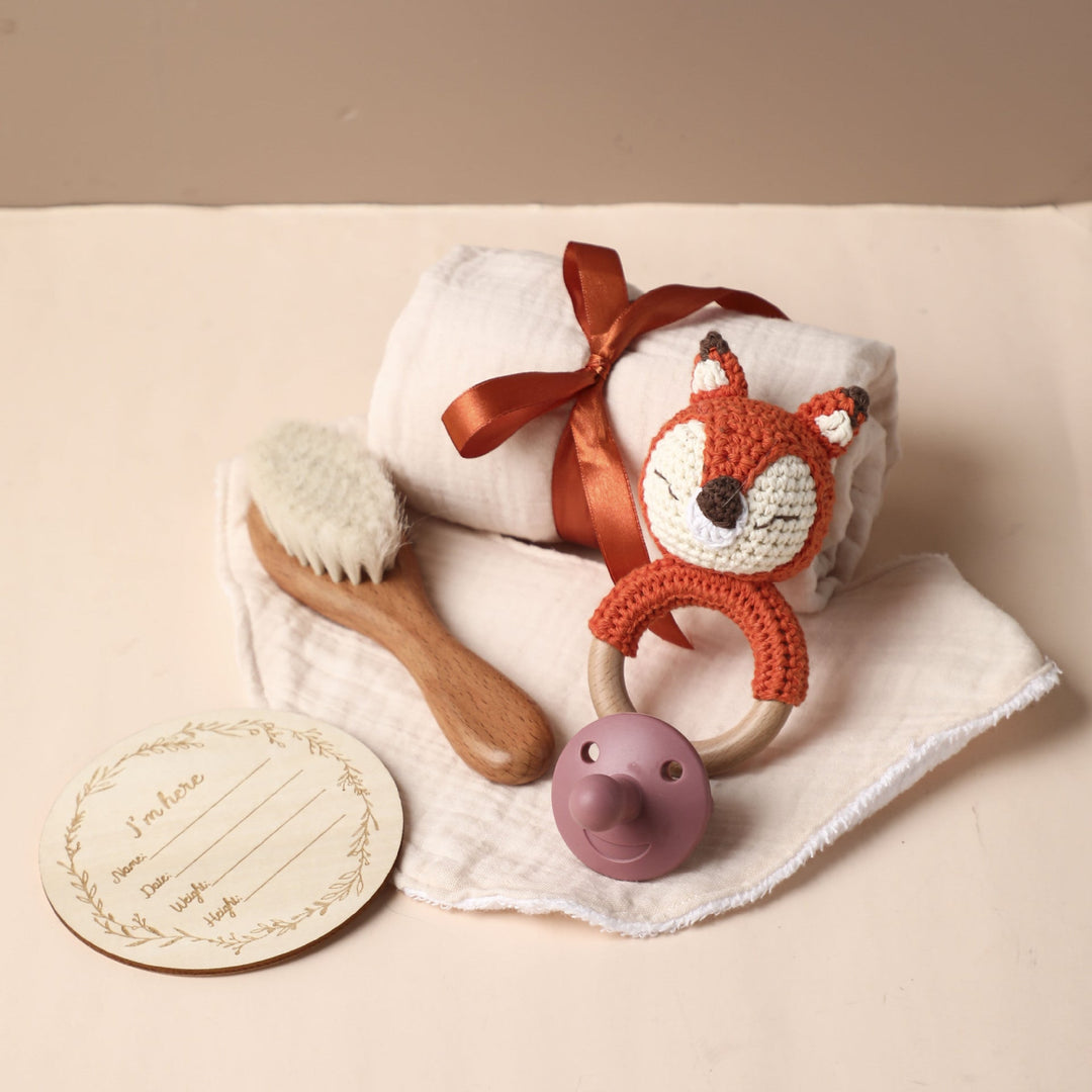 Sea Dragon Dreams baby gift set with fox crochet rattle, wooden brush, muslin towel, pacifier, and milestone card.