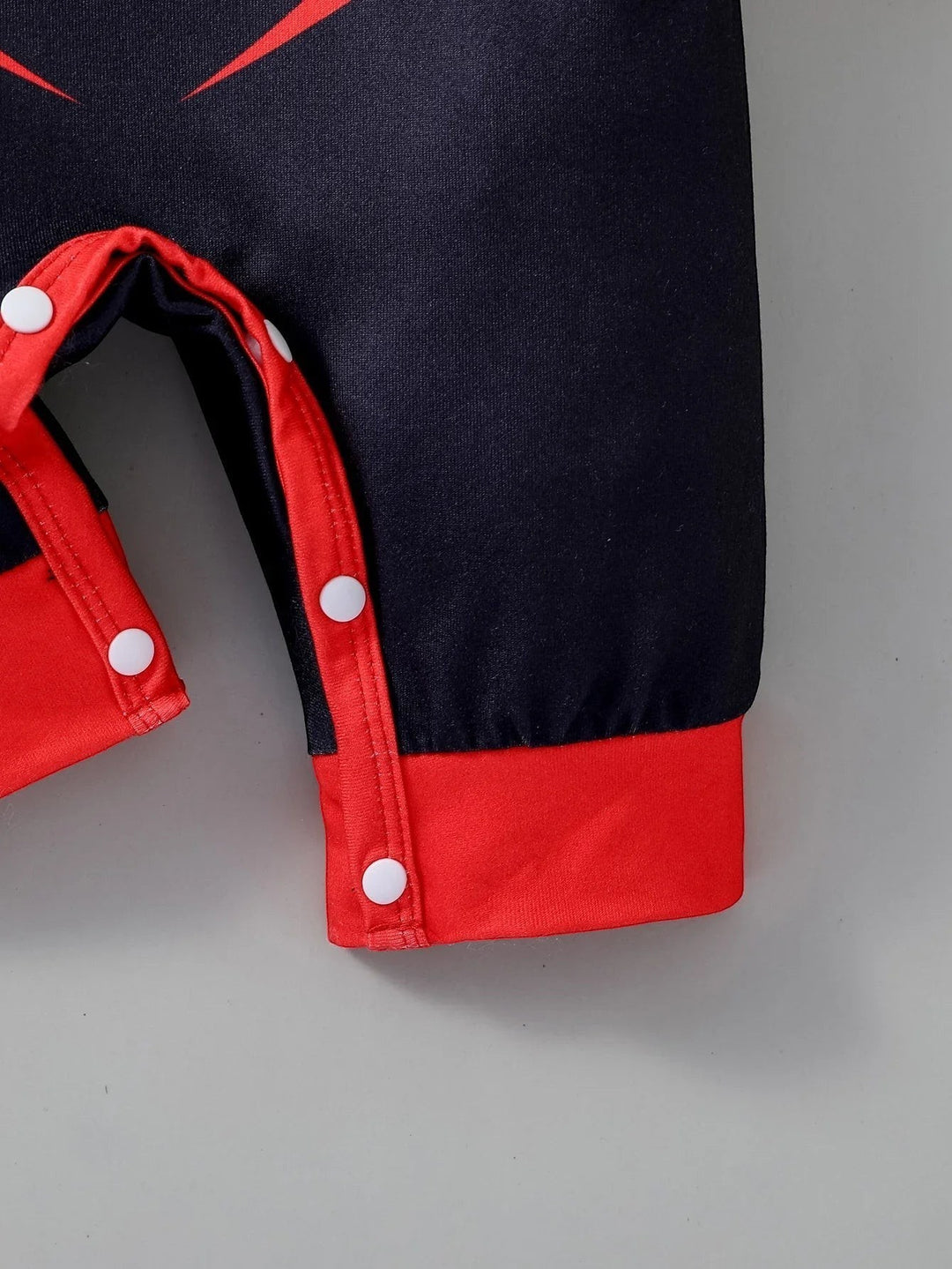 Sea Dragon Dreams baby jumpsuit in black and red with white snap buttons along the inner leg for easy diaper changes.
