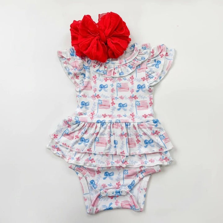 Sea Dragon Dreams bamboo flutter onesie with American flag print, ruffled neckline, tutu skirt, and red hair bow.