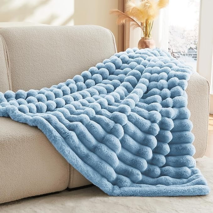 Sea Dragon Dreams BEDELITE light blue faux rabbit fur throw blanket with a 3D striped texture draped over a sofa.