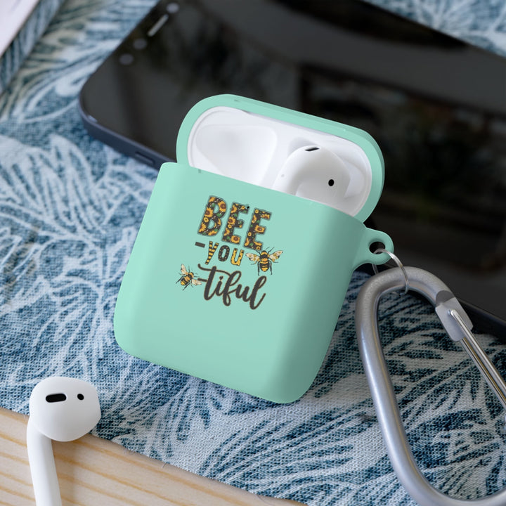 Sea Dragon Dreams Bee-You-Tiful floral AirPods case in mint green TPU with a metal carabiner on a patterned surface.