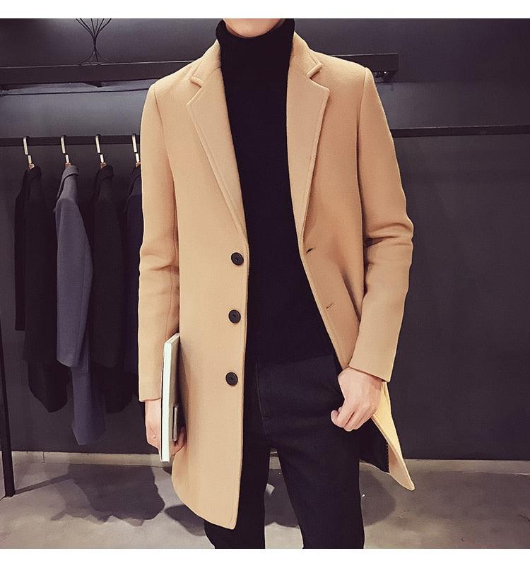Sea Dragon Dreams men's beige cotton trench coat with a turn-down collar, worn over a black turtleneck and trousers.