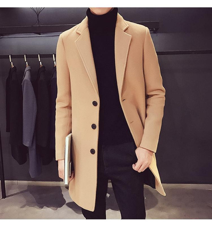 Sea Dragon Dreams men's beige cotton trench coat with a turn-down collar, worn over a black turtleneck and trousers.