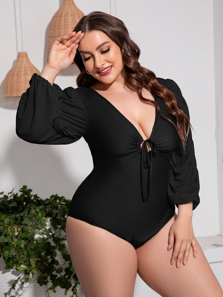 Sea Dragon Dreams plus size black one-piece swimsuit with deep V-neck, tie front, and long balloon sleeves.