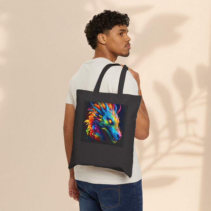 Man wearing a black Sea Dragon Dreams cotton canvas tote bag with a vibrant neon dragon graphic over his shoulder.