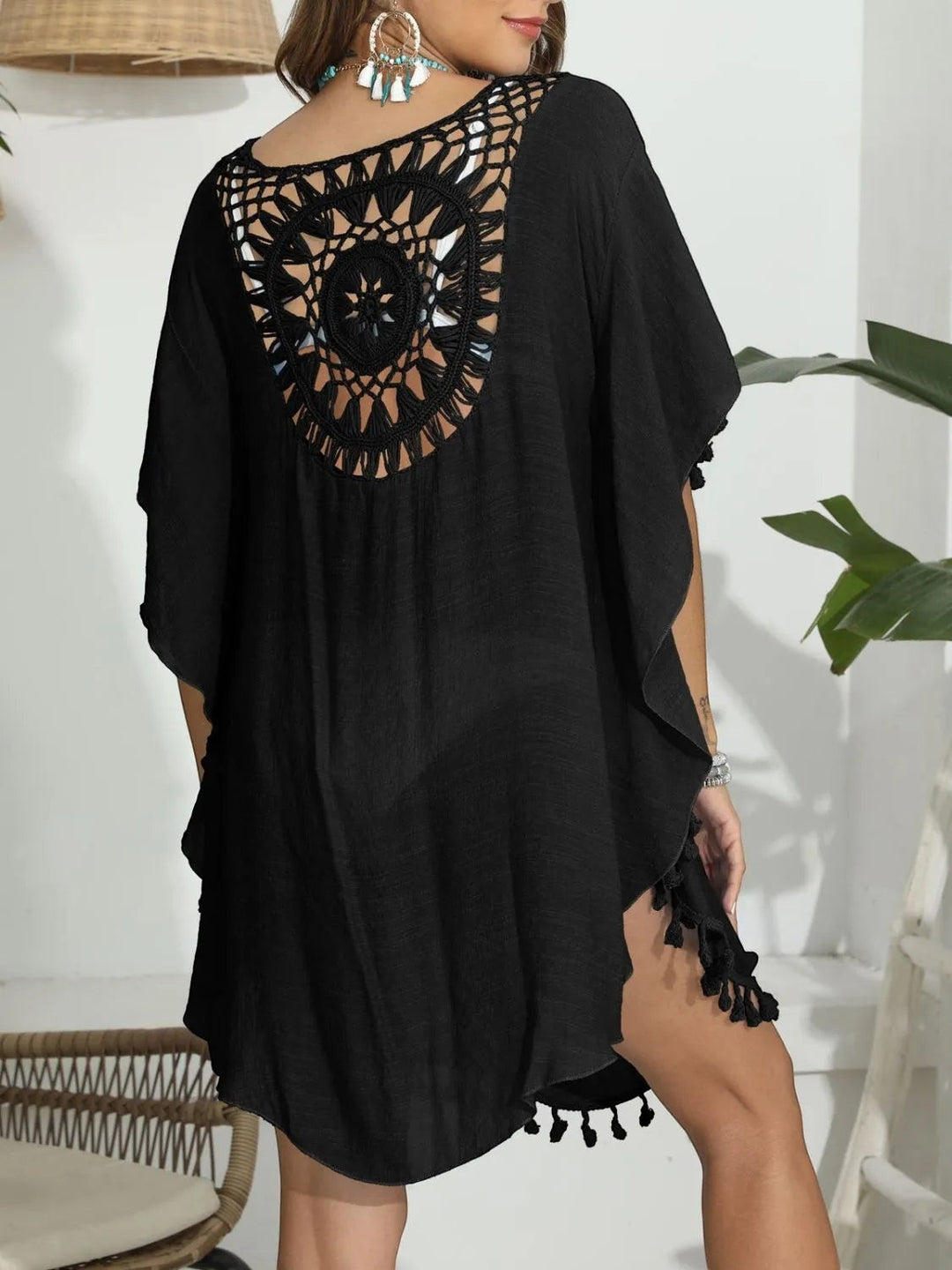 Sea Dragon Dreams black crochet beach cover-up with intricate back cutout, round neck, and playful tassel hem.