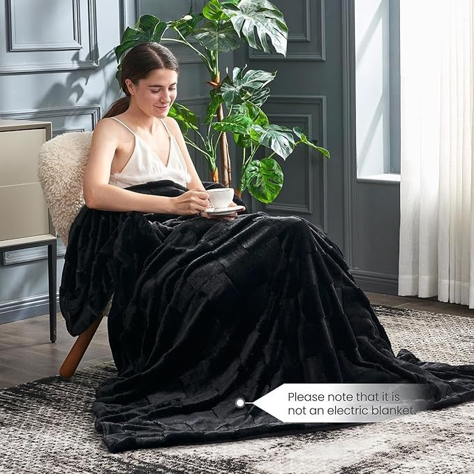 Sea Dragon Dreams black faux rabbit fur queen blanket with a checkered pattern draped over a woman in a cozy room.