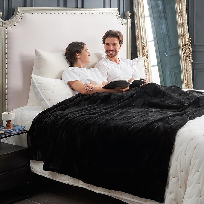 Sea Dragon Dreams black faux rabbit fur queen blanket with a checkered pattern draped over a couple in a bedroom.