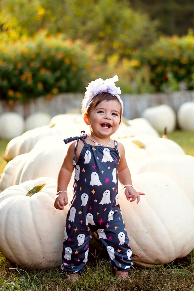 Sea Dragon Dreams Addison jumpsuit in black with white ghost and star print worn by a toddler in a pumpkin patch