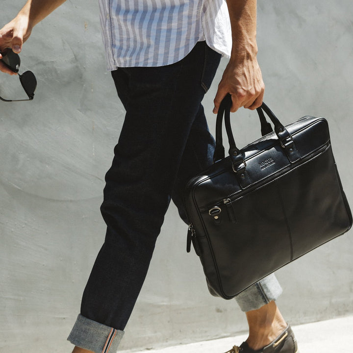 Sea Dragon Dreams black leather slim laptop bag carried by a man in casual office attire against a grey wall
