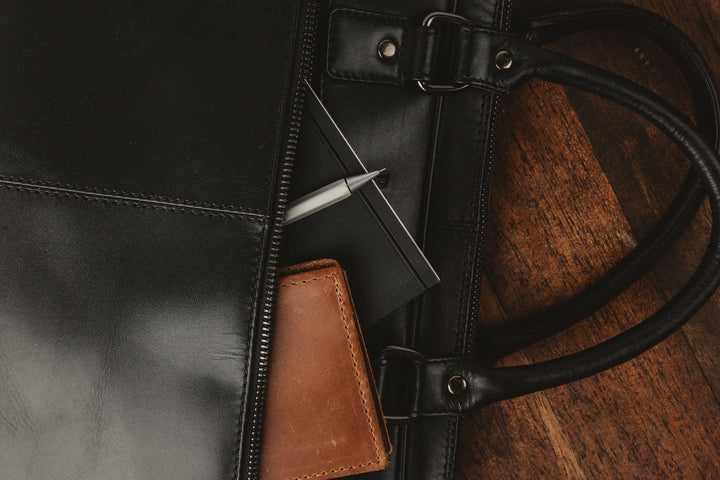 Sea Dragon Dreams black leather laptop bag with exterior zippered pocket containing a notebook and brown leather wallet