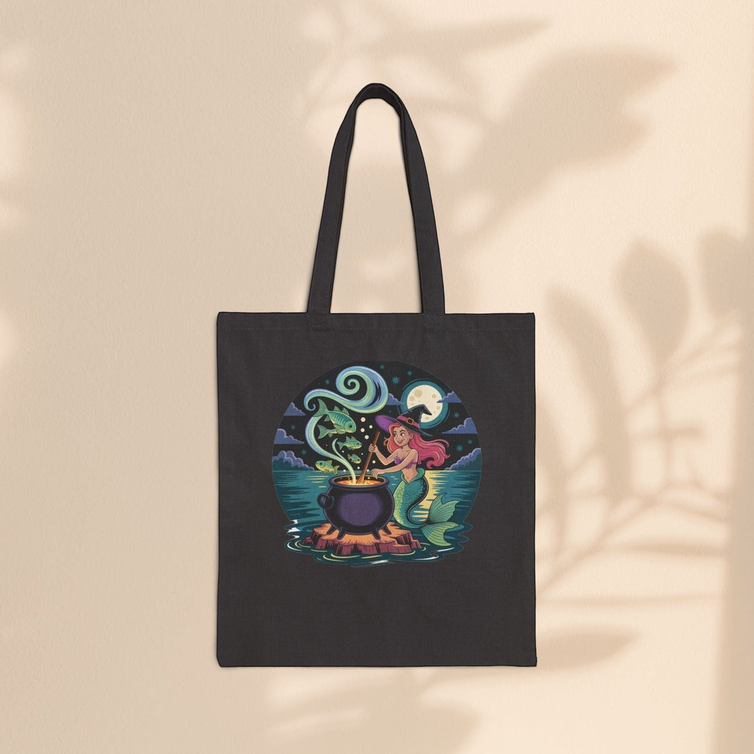 Sea Dragon Dreams black cotton canvas tote bag featuring a whimsical mermaid witch stirring a magical cauldron