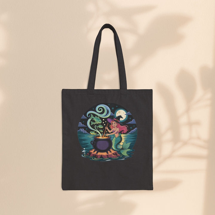 Sea Dragon Dreams black cotton canvas tote bag featuring a whimsical mermaid witch stirring a magical cauldron