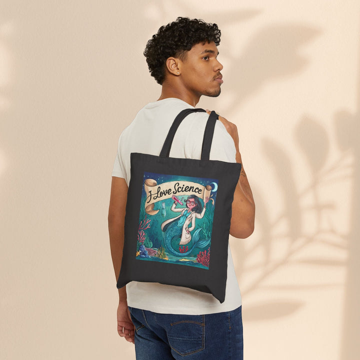 Sea Dragon Dreams black cotton canvas tote bag with I Love Science mermaid scientist print worn over a man's shoulder