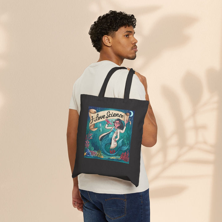 Sea Dragon Dreams black cotton canvas tote bag with I Love Science mermaid illustration worn by a man