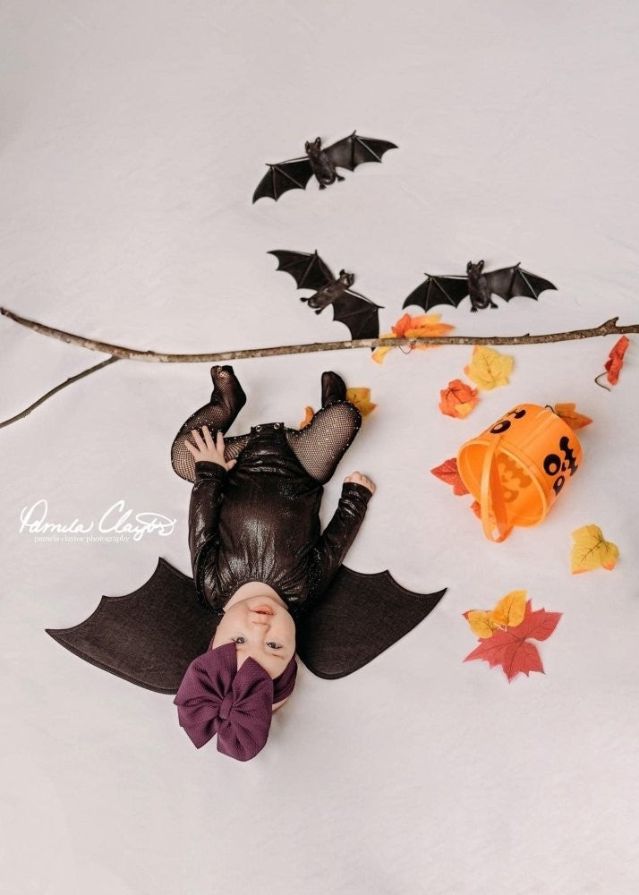 Sea Dragon Dreams baby wearing a shimmering black long sleeve leotard with bat wings for a Halloween costume