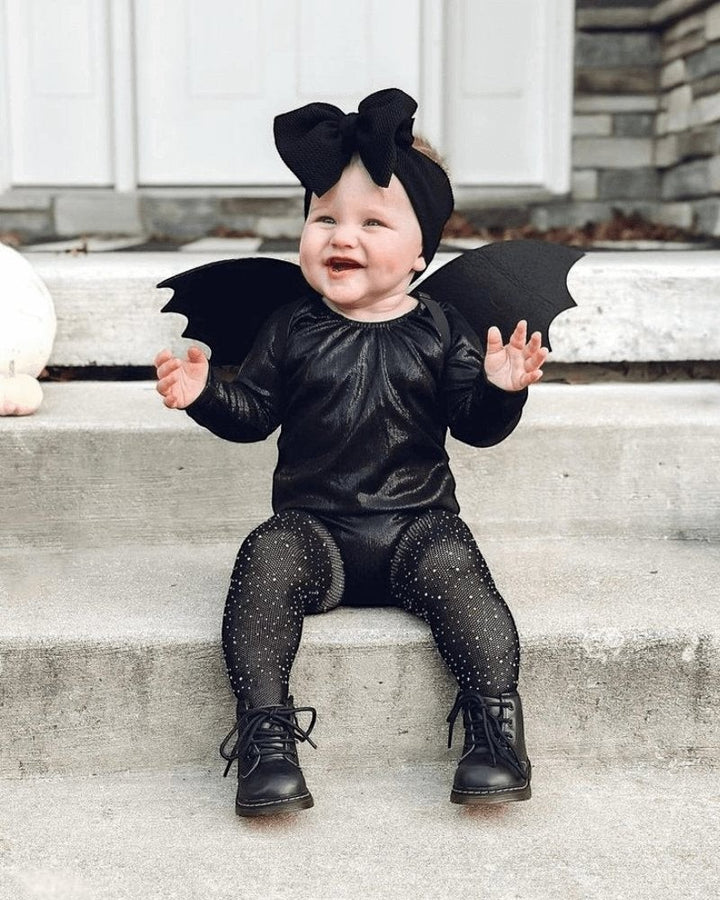 Baby wearing a Sea Dragon Dreams black shimmer long sleeve leotard as a bat costume with wings and a large hair bow