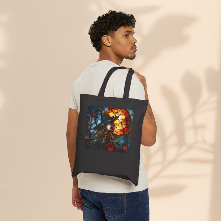 Man wearing a black Sea Dragon Dreams cotton canvas tote bag with a witchy Halloween stained glass print