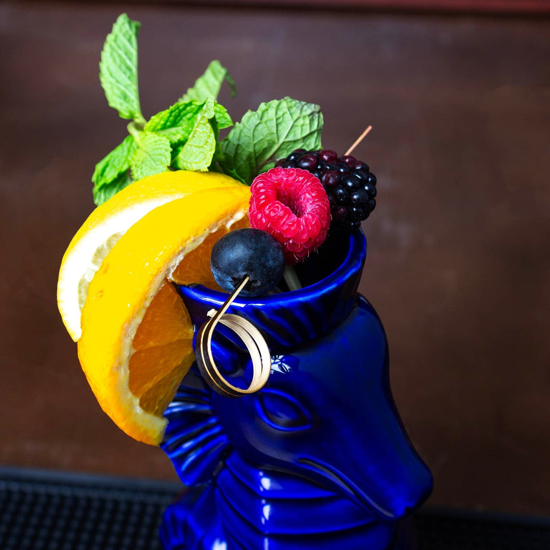 Sea Dragon Dreams ceramic dragon tiki mug in deep blue, garnished with fresh orange slices, mint, and mixed berries.