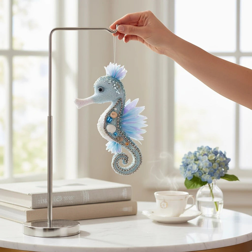 Sea Dragon Dreams Mark Roberts blue seahorse ornament with glitter, sequins, and iridescent fins hanging on a stand.