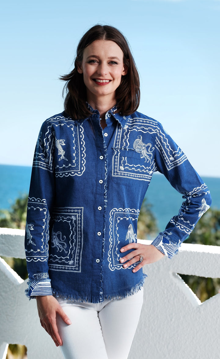 A woman wearing a Sea Dragon Dreams blue denim blouse with a white nautical sealife print and frayed hem at the coast