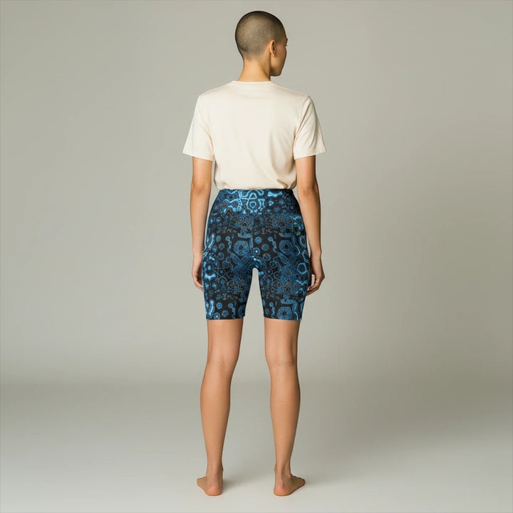 Sea Dragon Dreams women's workout shorts in shifting blue abstract print, worn with a beige t-shirt, back view.