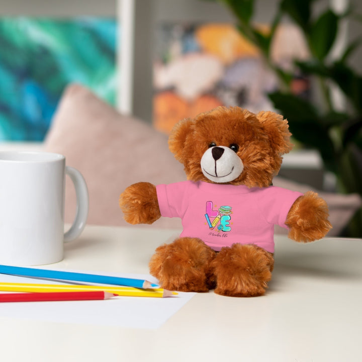Sea Dragon Dreams brown plush bear wearing a pink t-shirt with Love Teacher Life graphic on a desk with pencils