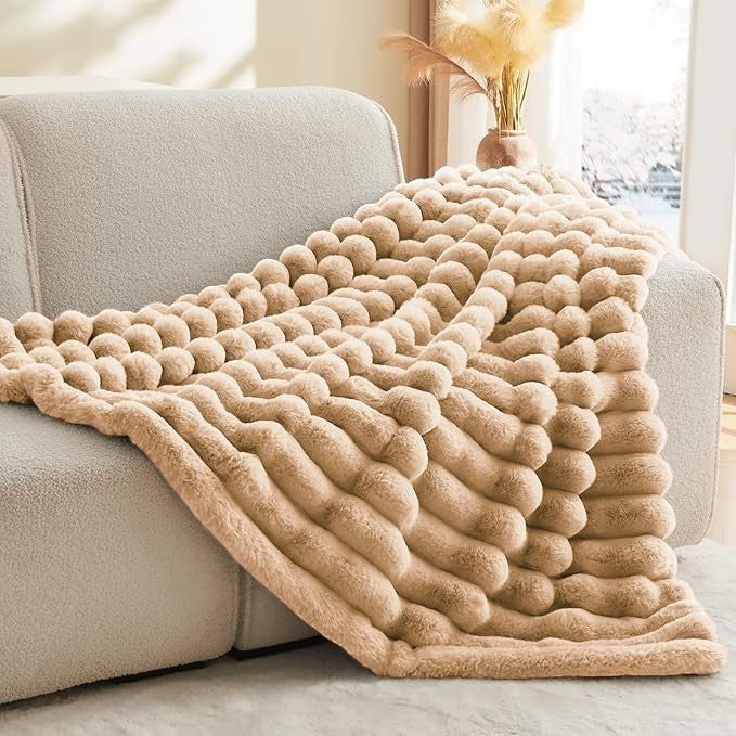 Sea Dragon Dreams BEDELITE brown faux rabbit fur throw blanket with a 3D striped texture draped over a modern sofa.