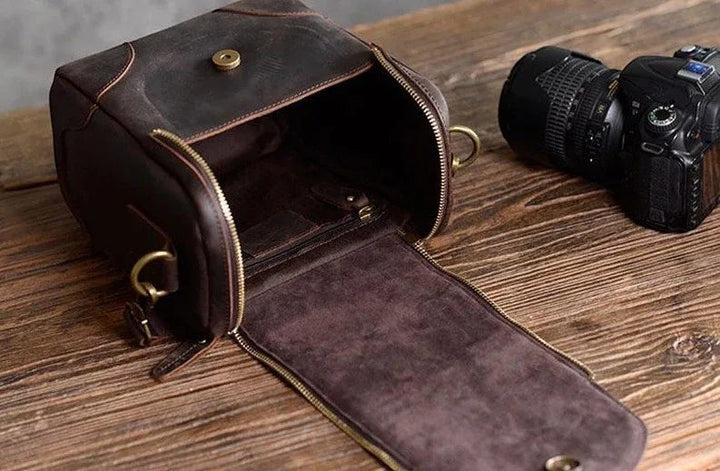 Sea Dragon Dreams The Calista dark brown full-grain leather camera bag with a zippered opening on a wooden table.