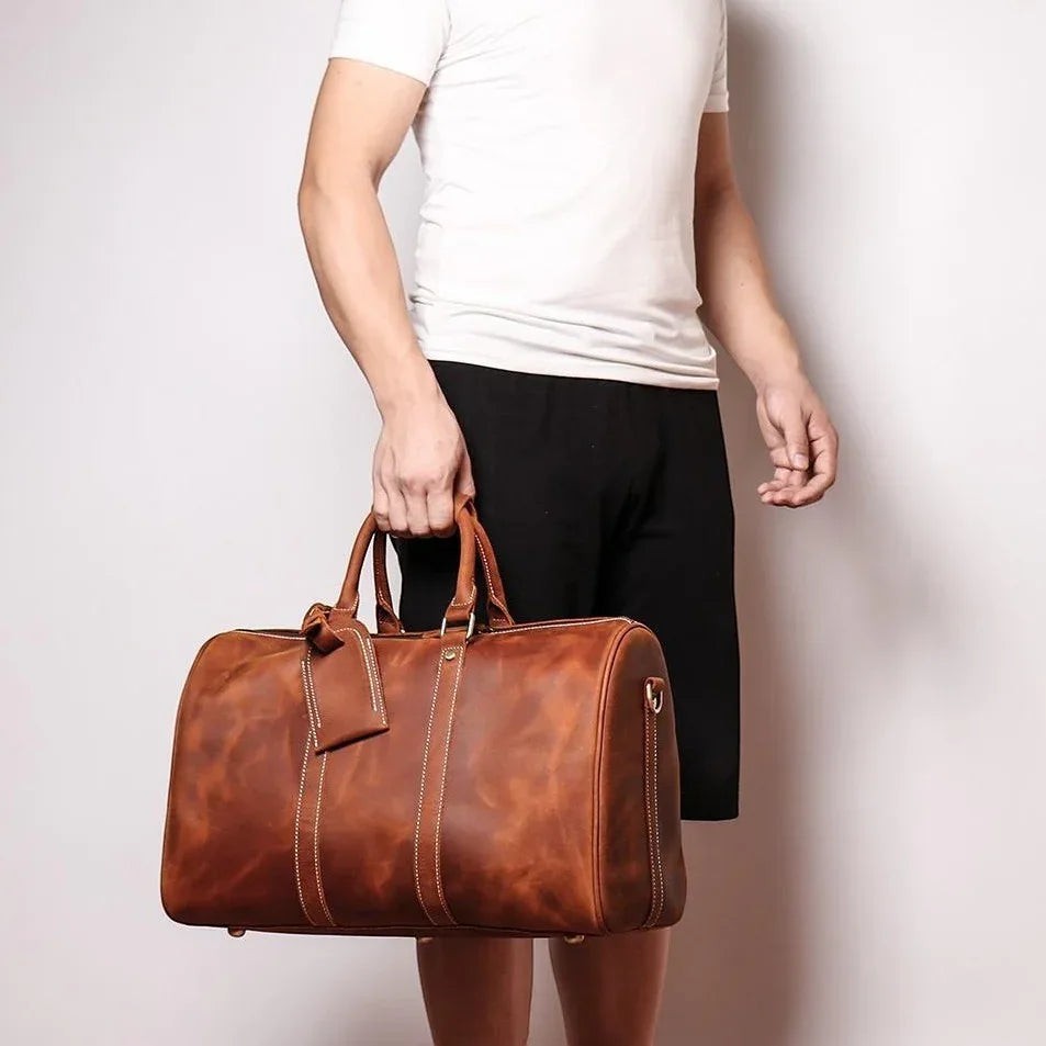 Sea Dragon Dreams Brandt Weekender brown horse leather duffle bag held by a man in a white t-shirt