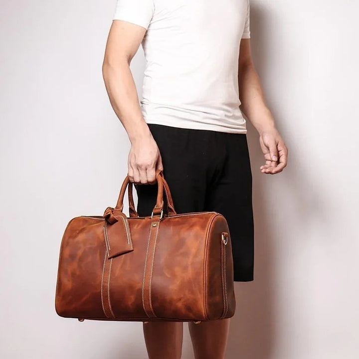 Sea Dragon Dreams Brandt Weekender brown horse leather duffle bag held by a man in a white t-shirt