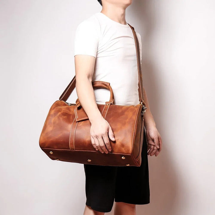 Sea Dragon Dreams Brandt Weekender small brown horse leather duffle bag with shoulder strap carried by a man