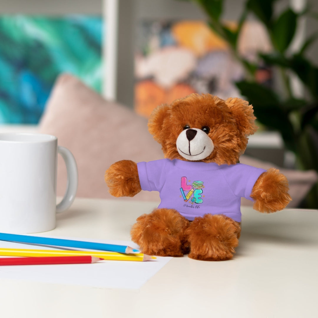 Sea Dragon Dreams brown teddy bear plush toy wearing a purple t-shirt with Love Teacher Life text on a desk