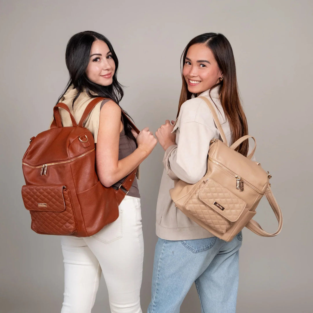 Two women wearing Sea Dragon Dreams caramel and beige vegan leather diaper bag backpacks with quilted front pockets.
