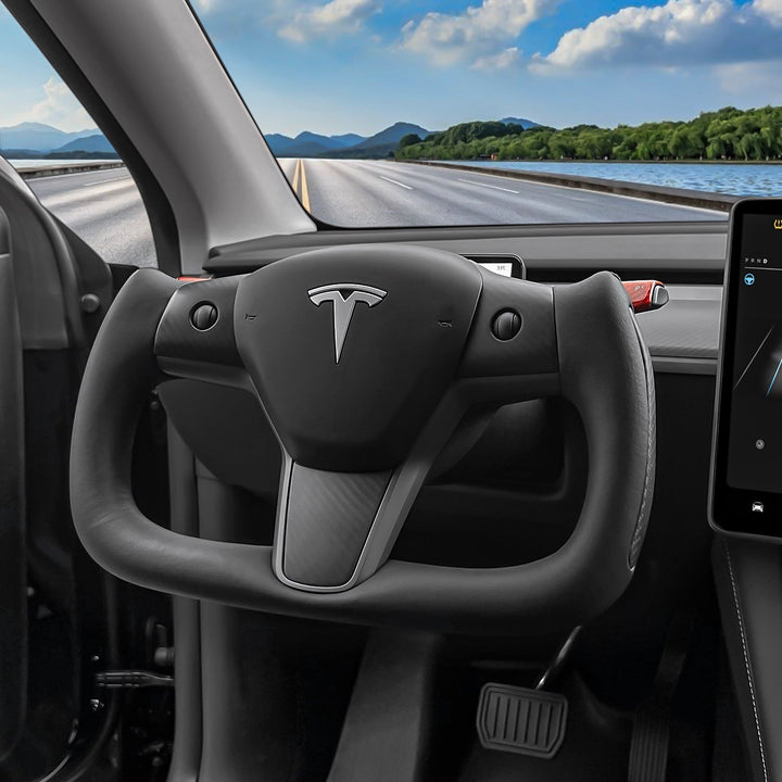 Sea Dragon Dreams carbon fiber yoke steering wheel installed in a Tesla Model 3 or Y interior with a road view.