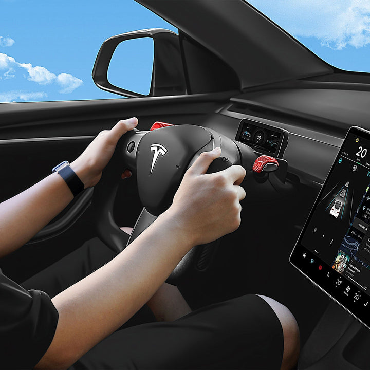 Sea Dragon Dreams carbon fiber yoke steering wheel installed in a Tesla Model 3 or Model Y, held by a driver.