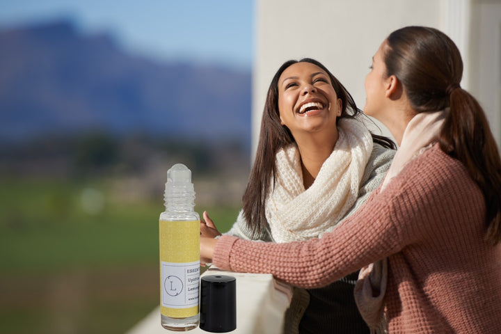 Sea Dragon Dreams CBD essential oil roll-on with crystals held by two laughing women outdoors in a scenic setting.