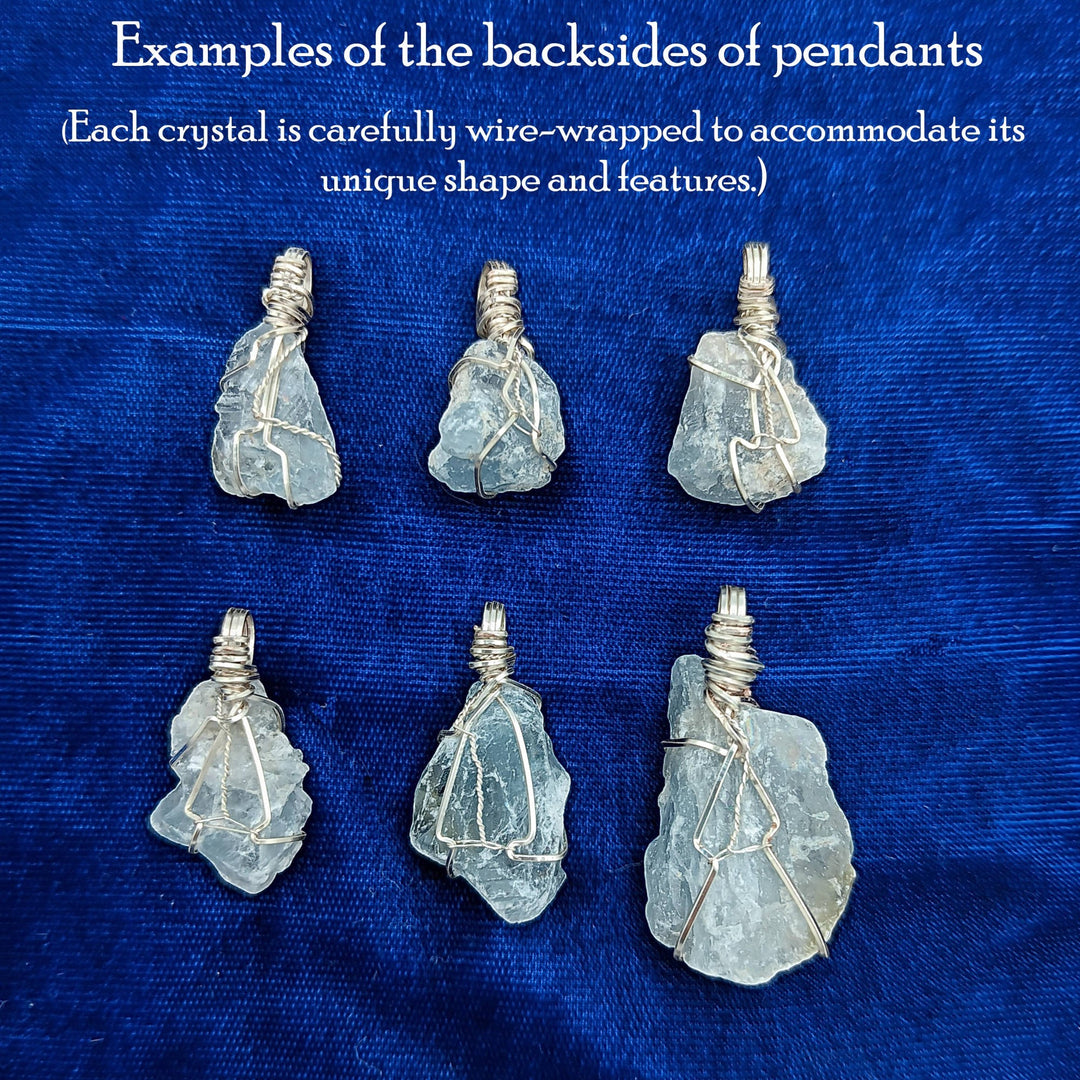 Sea Dragon Dreams raw celestite crystal pendants showing silver-plated wire-wrapped backs on a blue velvet background.