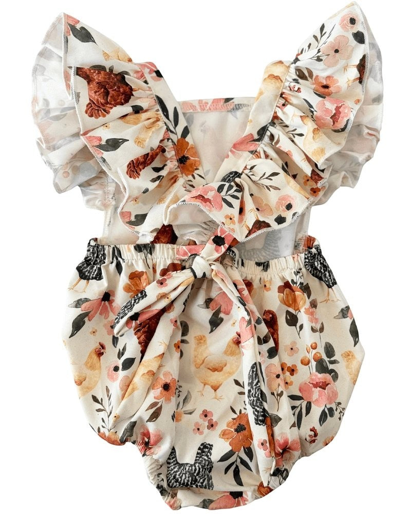 Sea Dragon Dreams baby romper in cream with a whimsical chicken and floral print, featuring ruffle back straps and a bow.