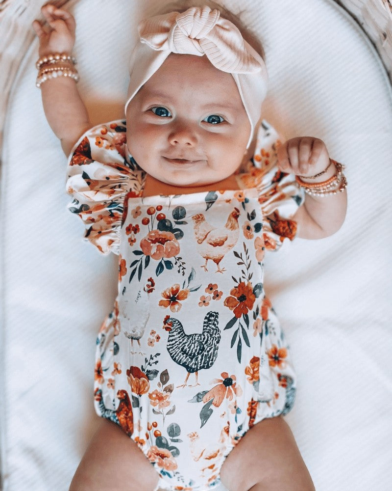 Sea Dragon Dreams baby romper with chicken and floral print, featuring ruffle sleeves and a comfortable polyester fit.