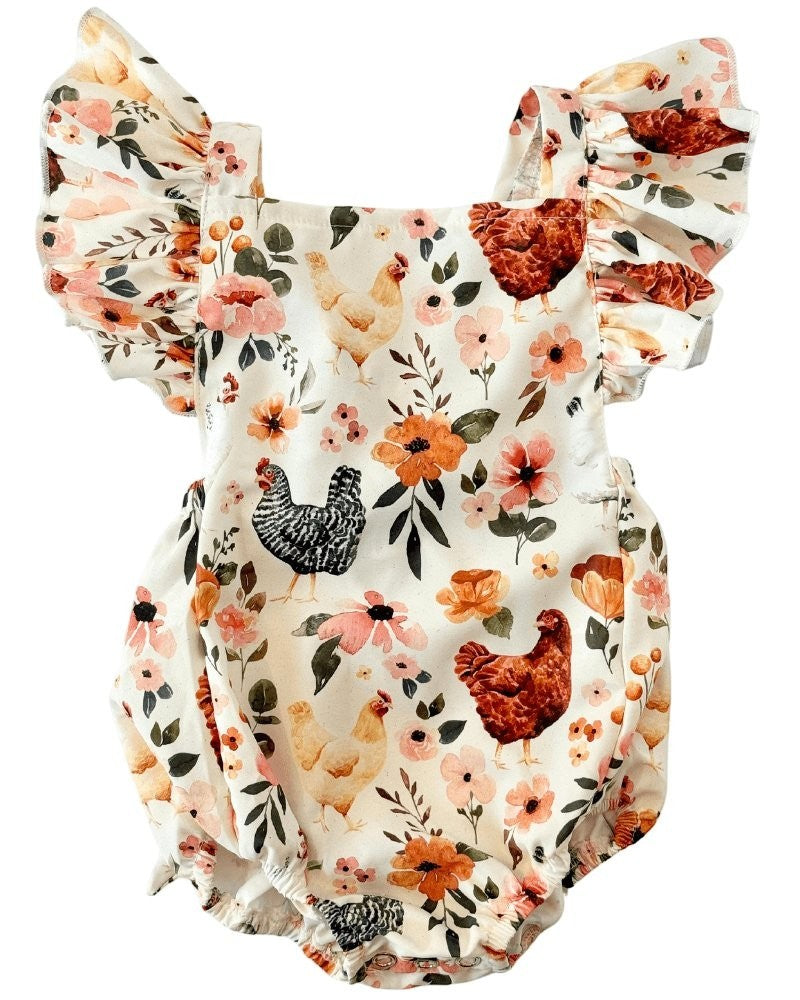 Sea Dragon Dreams baby romper in cream with a whimsical chicken and floral print, featuring ruffled shoulder straps.