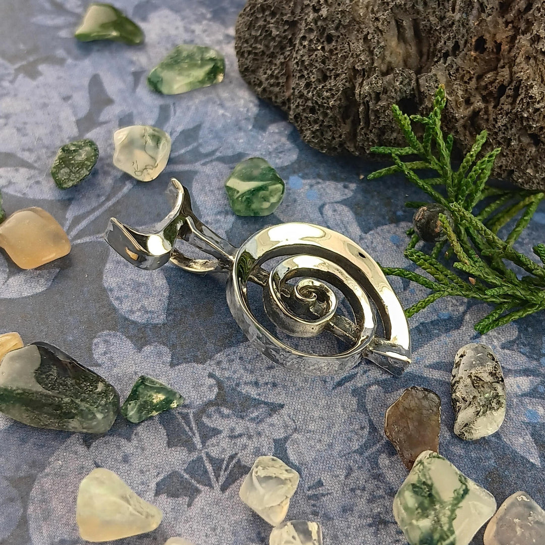 Sea Dragon Dreams handmade sterling silver Cho Ku Rei Reiki pendant with a sculptural spiral design on a blue surface.