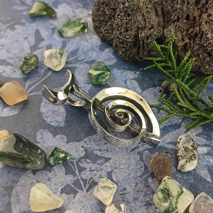 Sea Dragon Dreams handmade sterling silver Cho Ku Rei Reiki pendant with a sculptural spiral design on a blue surface.