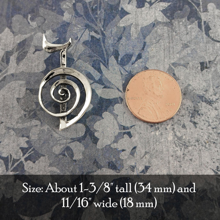Sea Dragon Dreams handmade sterling silver Cho Ku Rei Reiki pendant next to a US penny for scale on a floral fabric.