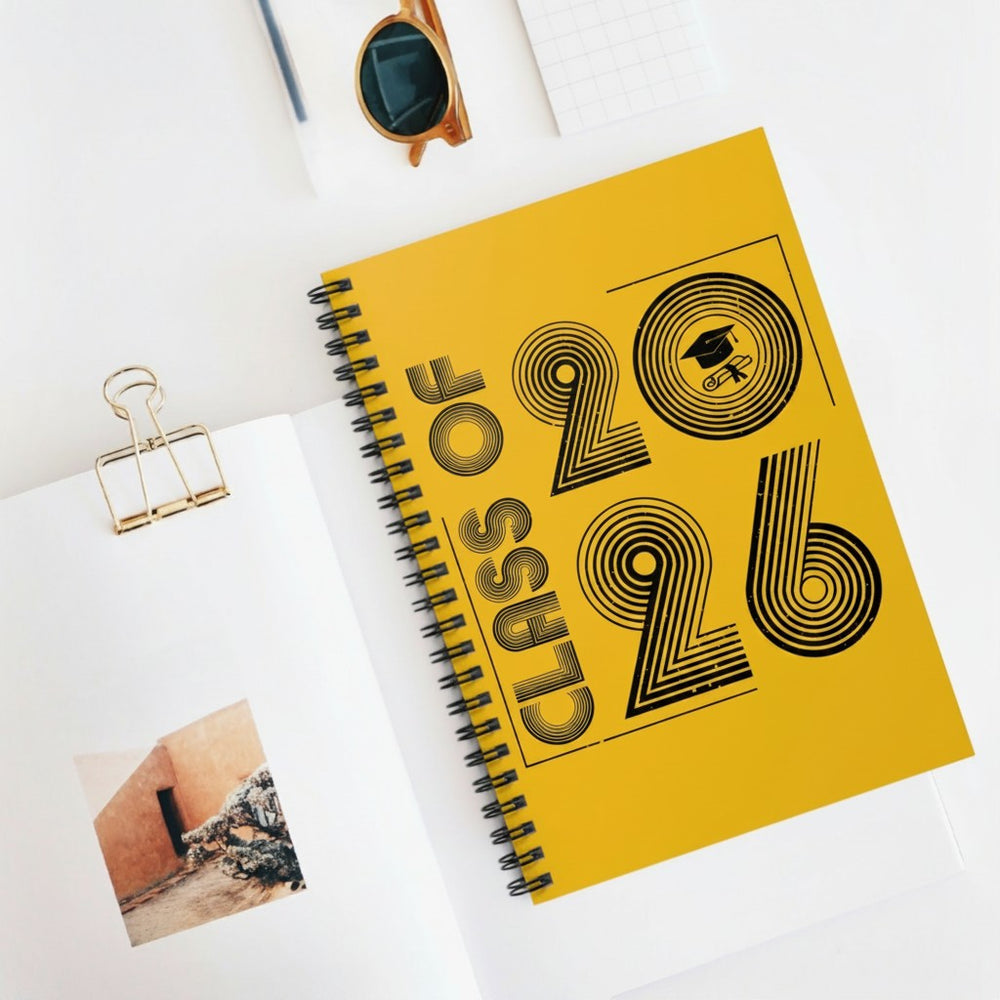 Sea Dragon Dreams Class of 2026 yellow spiral notebook with black typography and graduation cap icon on white desk.