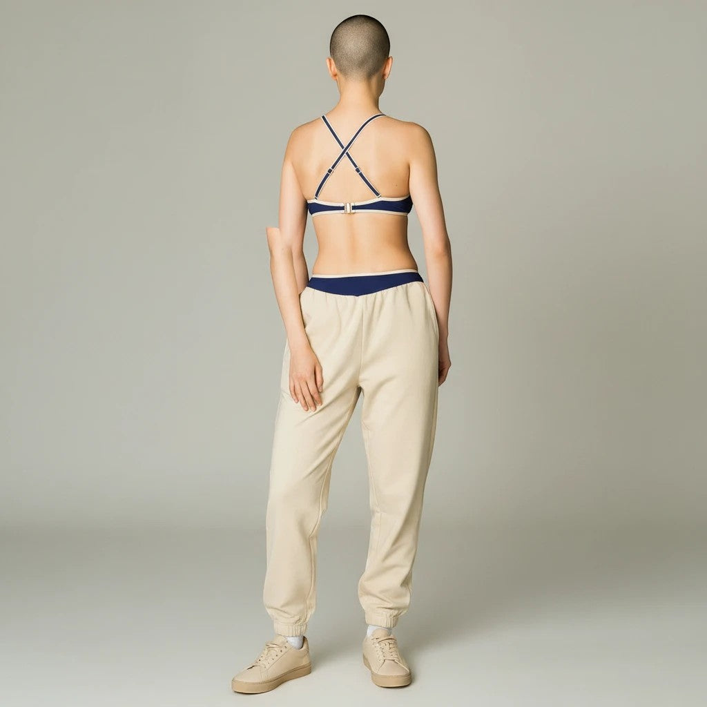 Sea Dragon Dreams bikini top with navy blue contrast trim and T-back straps worn by a model in beige sweatpants