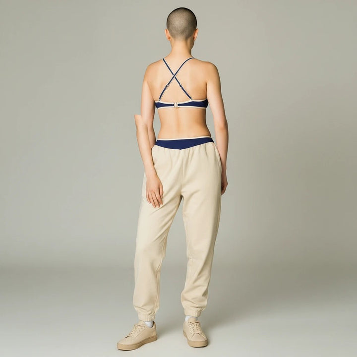 Sea Dragon Dreams bikini top with navy blue contrast trim and T-back straps worn by a model in beige sweatpants